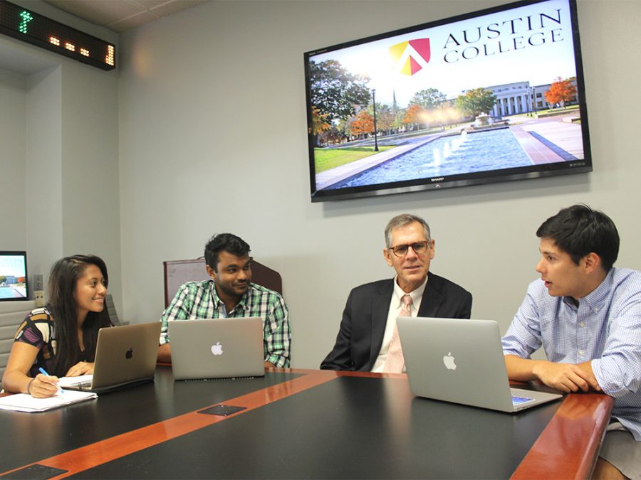 Three students with laptops exchaning ideas with the Professor in the Economics & Business Administration